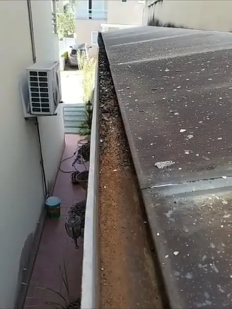 Calha entupida de folhas e terra sendo limpa por Carlos Pessoa em Cotia - SP